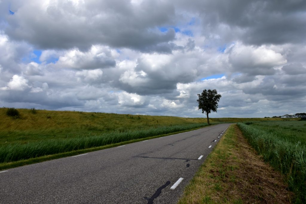 Weg over een dijk in Nederland onder een bewolkte lucht